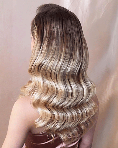 Rückansicht von langem, glänzendem Haar mit weichen Wellen in Blond-Braun-Tönen