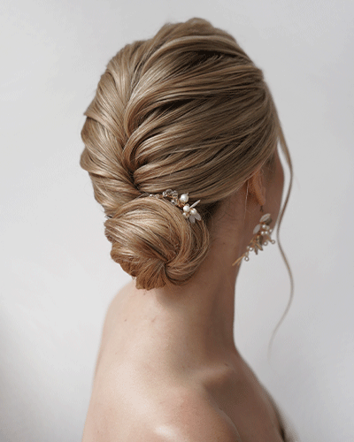 Elegante Brautfrisur im Nacken zu einem Chignon gesteckt, mit Haarschmuck verziert