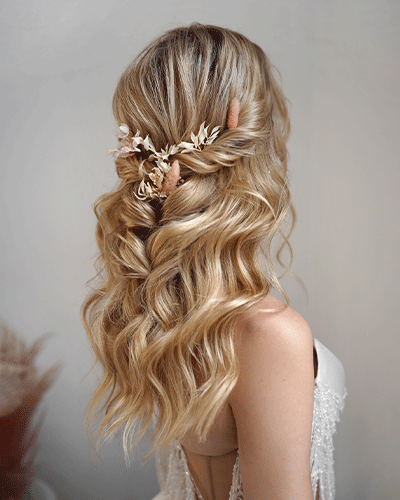 Rückansicht einer romantischen Brautfrisur mit offenen Locken und Blumen-Haarschmuck