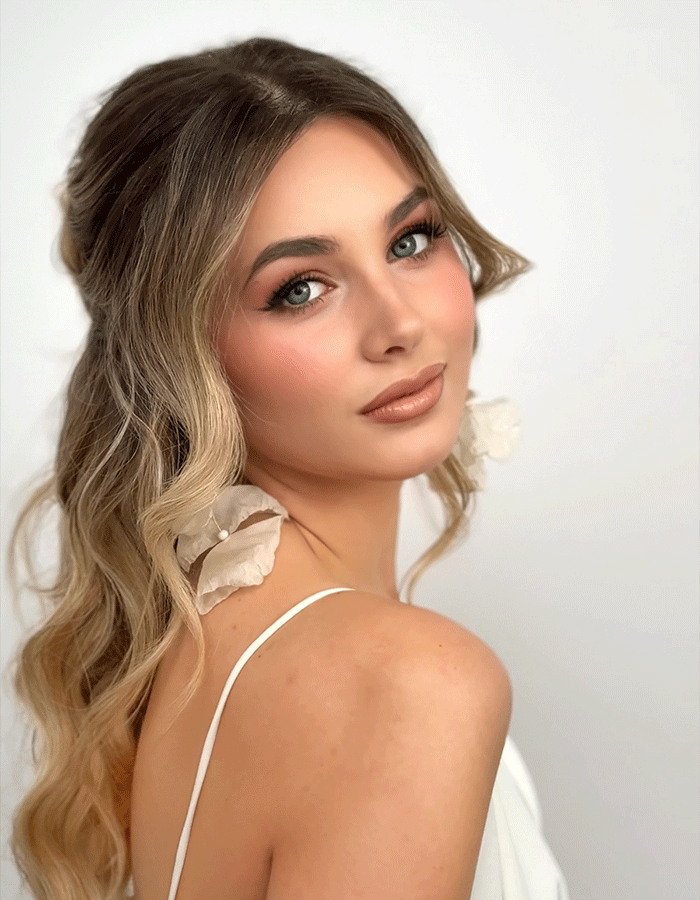 Junge Frau mit eleganter Frisur und natürlichem Make-up posiert seitlich zur Kamera