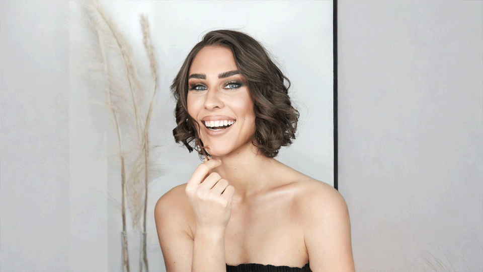 Nahaufnahme einer lachenden Frau mit kurzem, gewelltem Bob und elegantem Event-Make-up